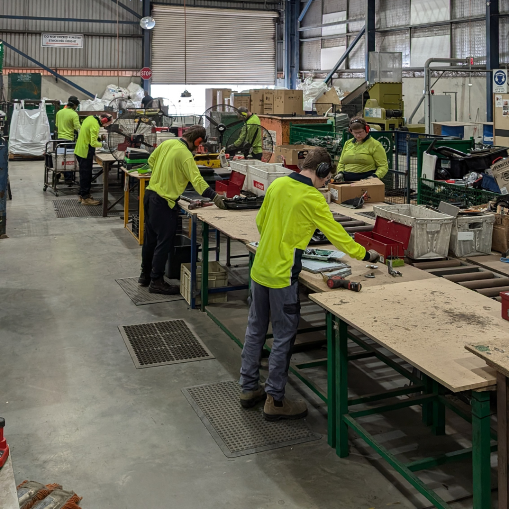 People working on a warehouse floor sorting electronic waste