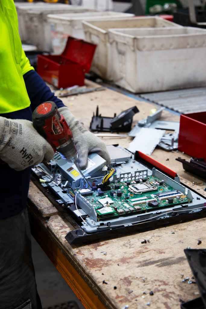 Two hands working on an open piece of electronic waste